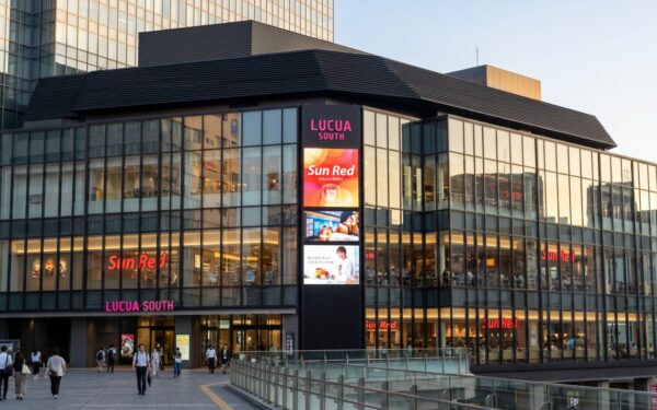 Modern commercial building Lucua South features vibrant signage and bustling pedestrians, showcasing a lively shopping experience.