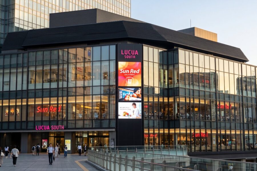 Modern commercial building Lucua South features vibrant signage and bustling pedestrians, showcasing a lively shopping experience.