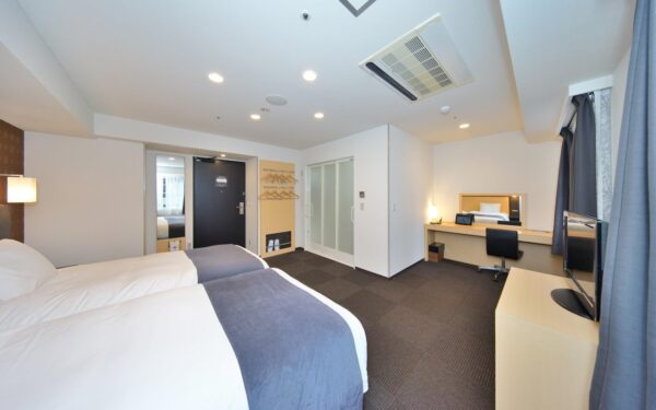 Modern hotel room featuring twin beds, a workspace, and stylish decor, ideal for business travelers or leisure stays.