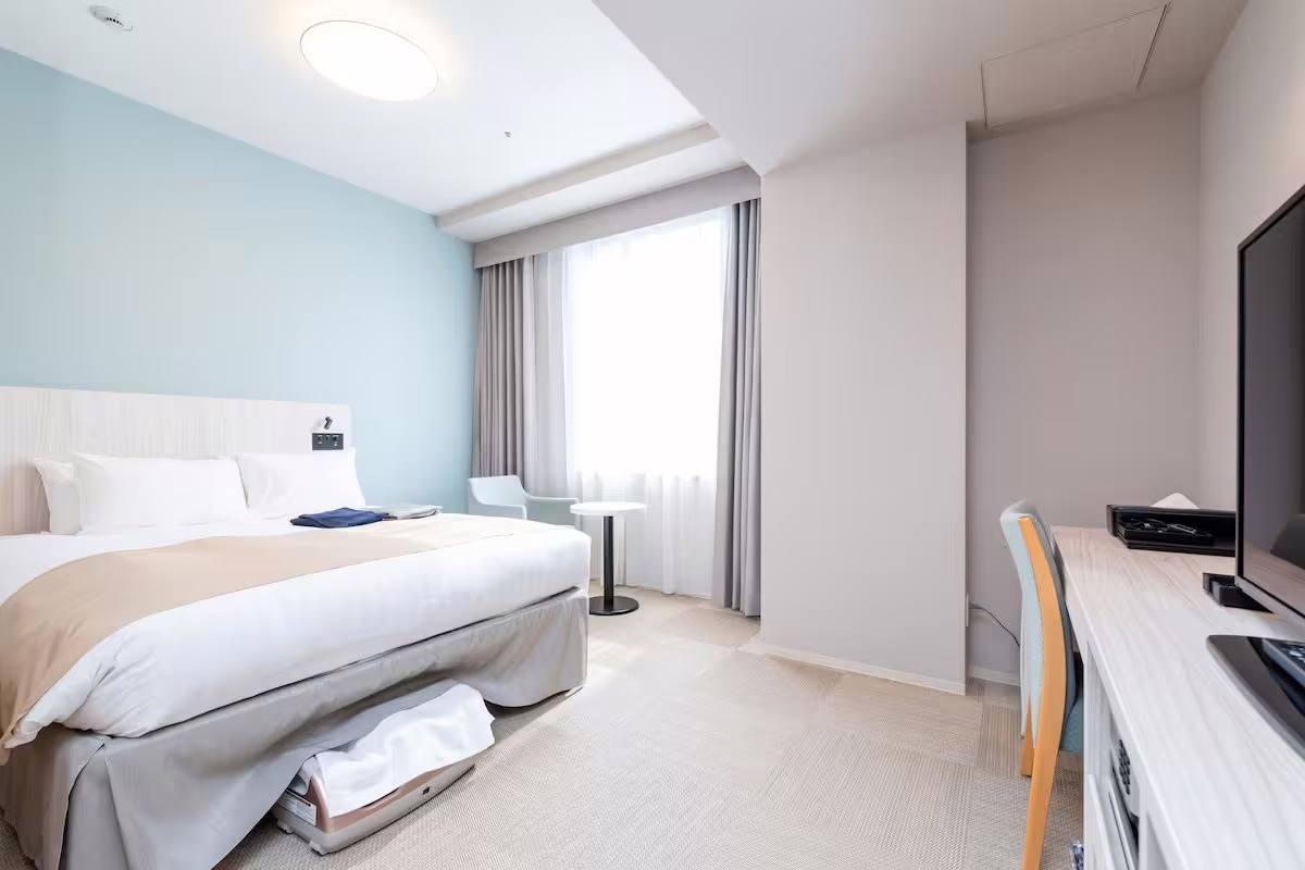 Modern Hiyori Hotel stands among urban buildings, representing contemporary hospitality in a bustling cityscape.
