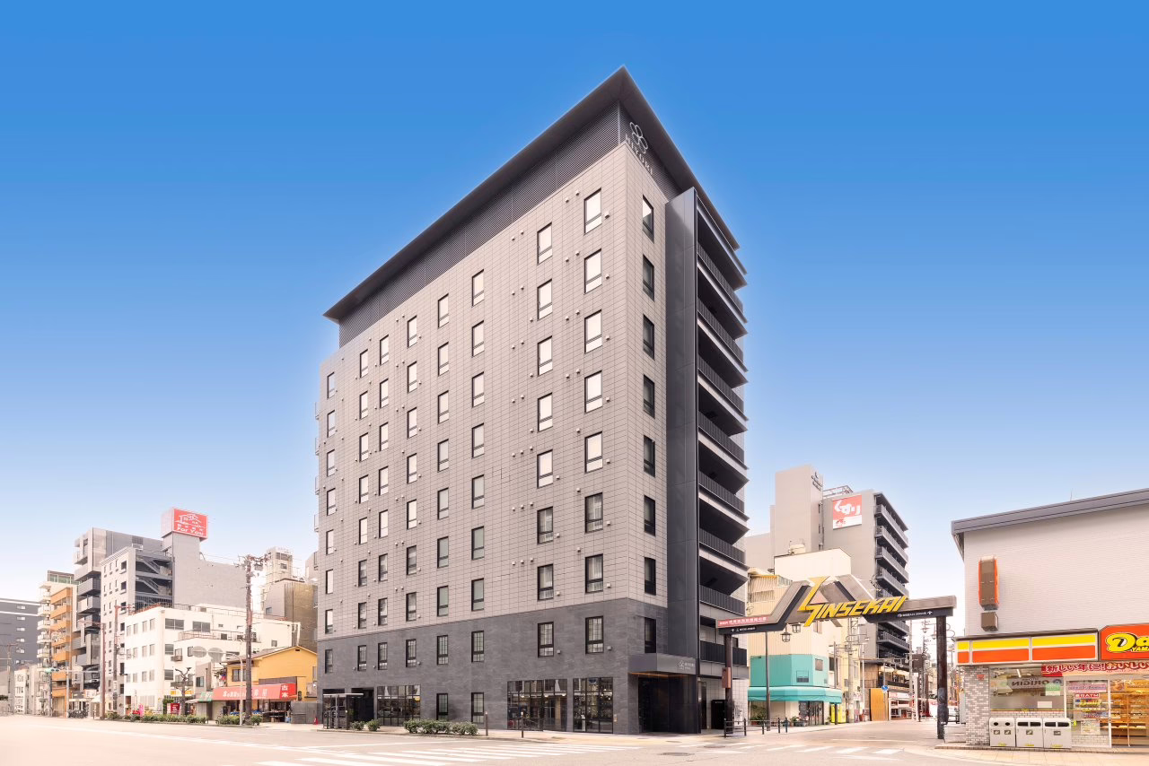 Modern gray hotel building in a bustling urban area, showcasing contemporary architecture amid city backdrop.