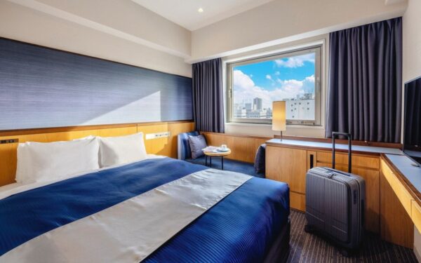 Modern hotel room with a king-sized bed, city view, and cozy seating area, ideal for travelers seeking comfort and style.