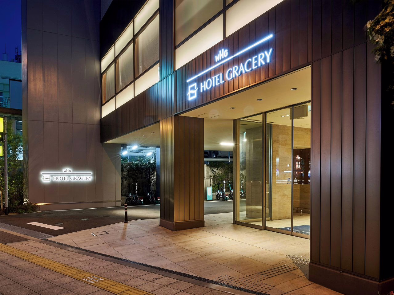 Modern hotel entrance of Hotel Gracery, showcasing a sleek design and inviting ambiance in an urban setting at night.