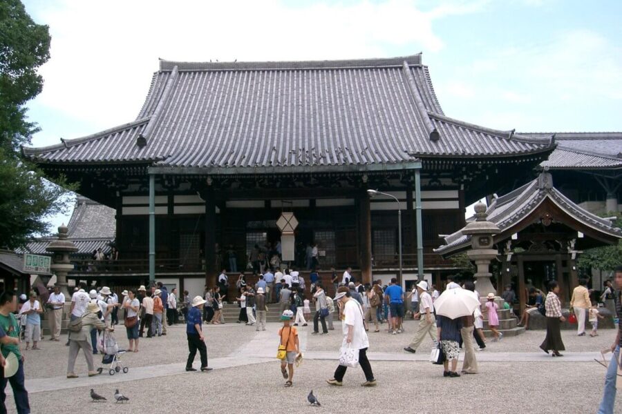 Crowds visiting a traditional Japanese temple, enjoying the serene environment and cultural heritage on a sunny day.