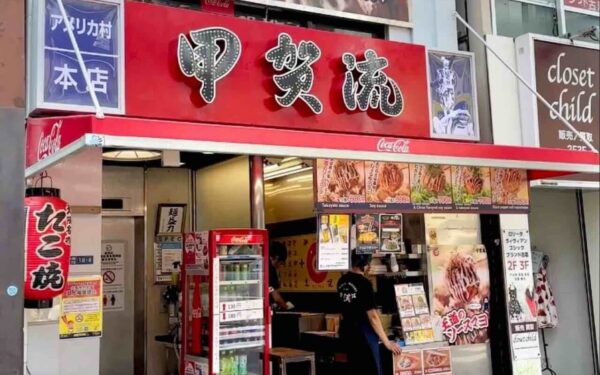 Popular street food stall in Japan, featuring vibrant signage and a menu highlighting takoyaki and other local dishes.