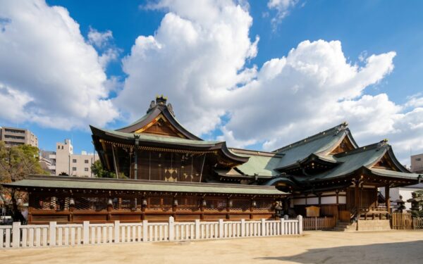 Traditional Japanese shrine with ornate architecture amidst urban landscape, symbolizing cultural heritage and tranquility.