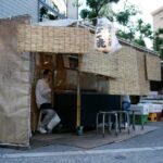 Traditional Japanese food stall with a vendor preparing meals, creating an inviting atmosphere for street food lovers.