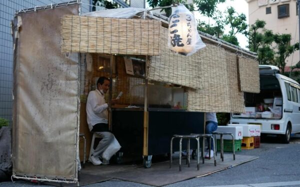 Traditional Japanese food stall with a vendor preparing meals, creating an inviting atmosphere for street food lovers.