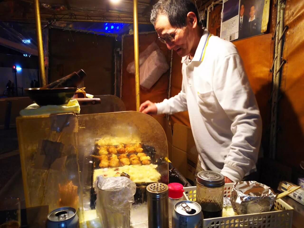 Street vendor serves hot takoyaki at night, creating a lively atmosphere filled with delicious street food delights.