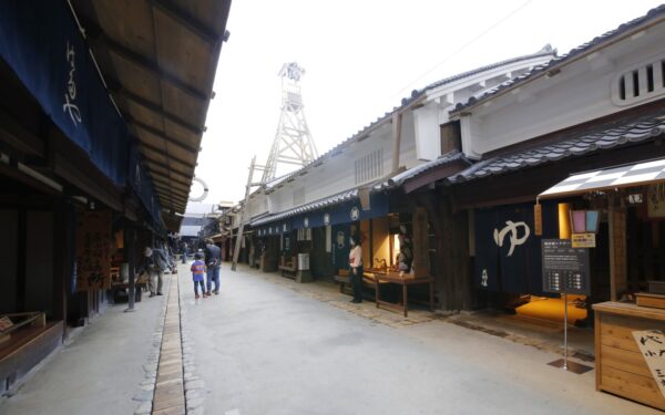 Traditional Japanese street with shops, a child and adult walking, showcasing cultural heritage and local craftsmanship.