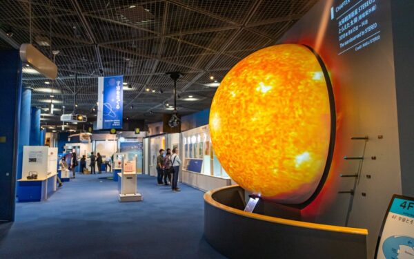 Interactive science exhibit showcasing a large, vibrant model of the sun with visitors exploring space-related displays.
