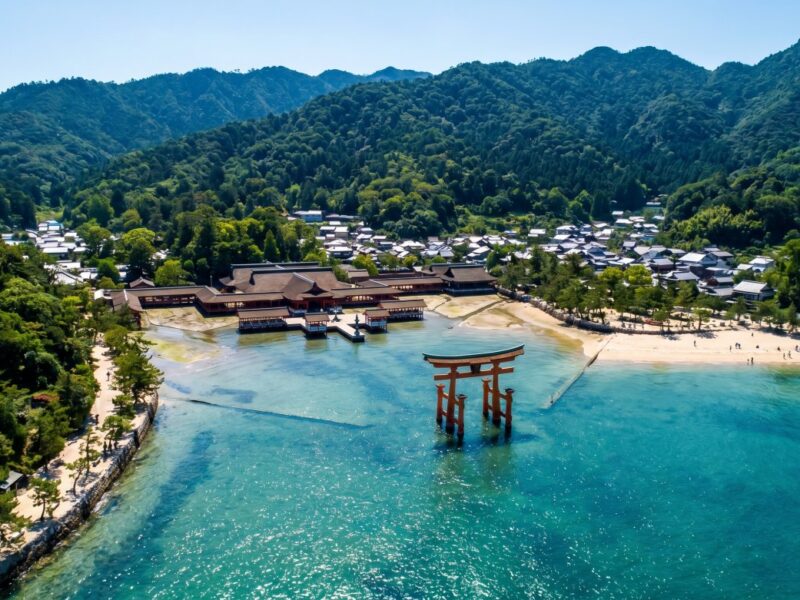 The iconic red torii gate stands majestically in the clear waters, symbolizing traditional Japanese spirituality against a serene landscape.